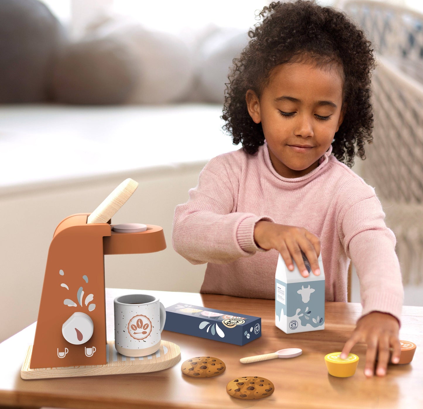 Child playing with a toy coffee set on a table
