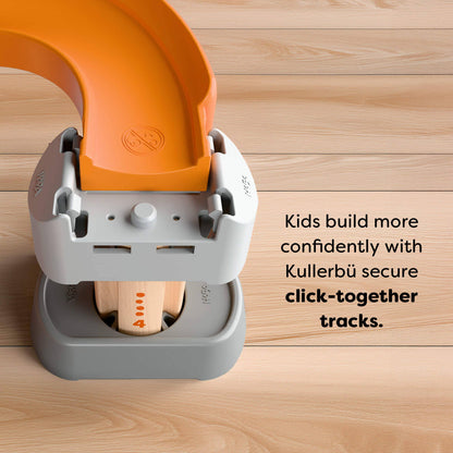 Children's building toy with orange and gray components on a wooden surface, featuring Kullerbü branding.