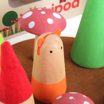 Wooden toy with a red mushroom cap on a brown surface