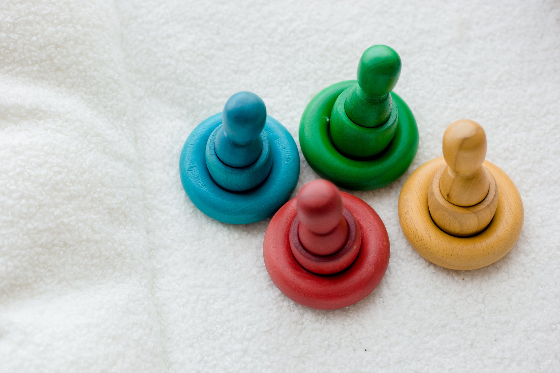 Four colorful wooden toys on a textured surface