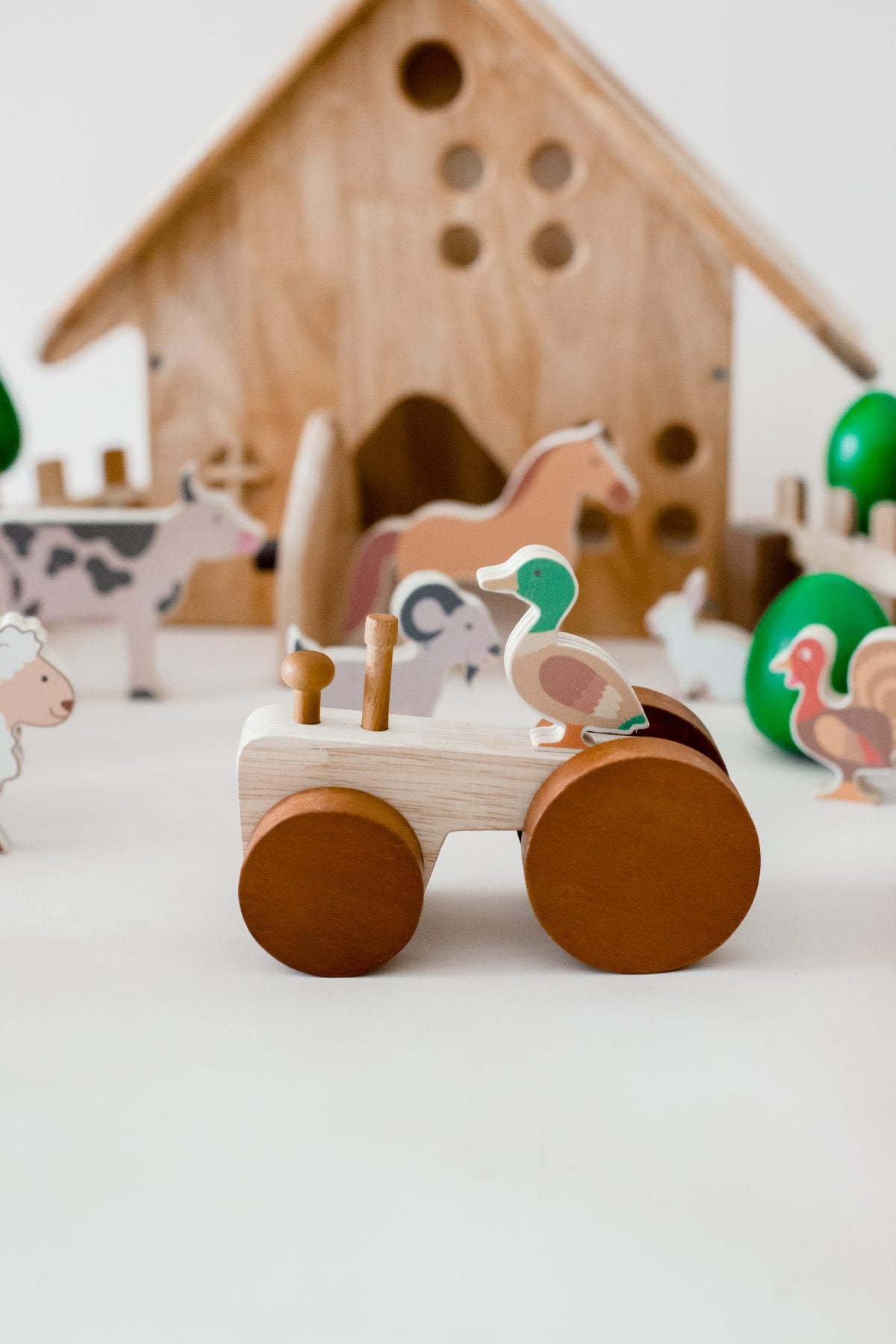 Wooden toy farm set with animals and a barn on a white background